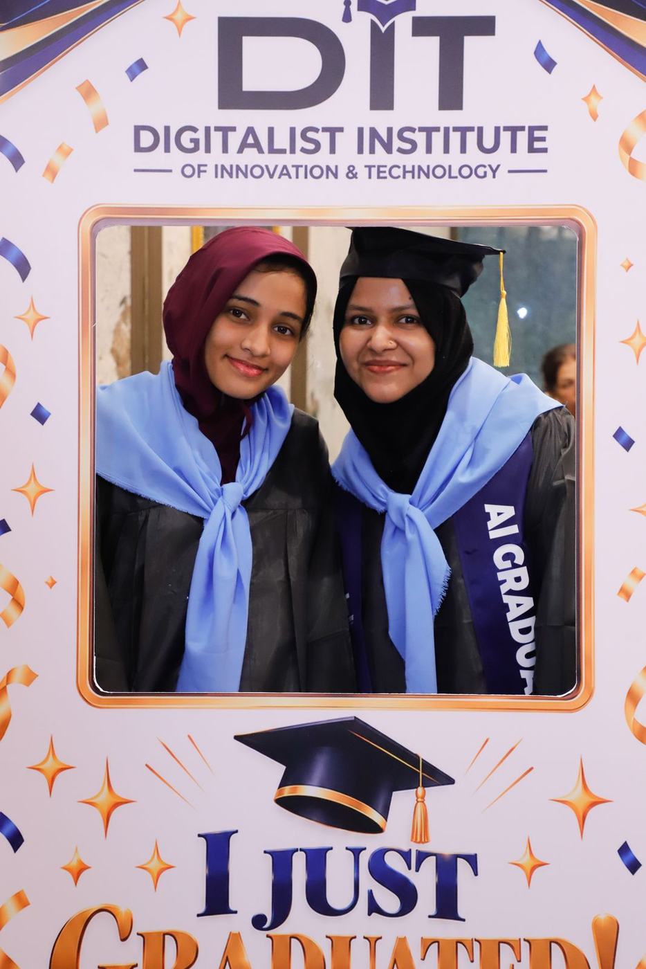 Two graduates in the 'I just graduated' photo frame